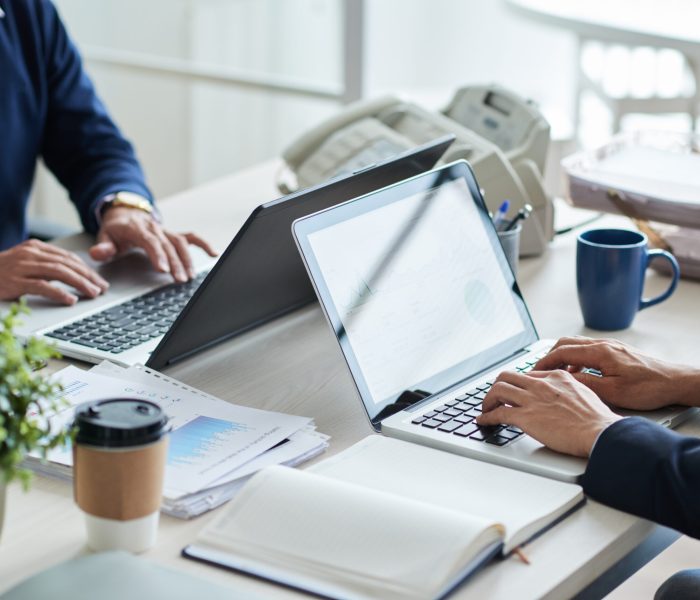 Cropped image of business people working on laptops in office
